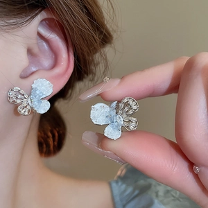 Macro detail of silver bow earrings with sparkling zircons and pearl accents on model