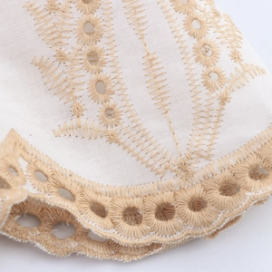 Close-up of white vacation style maxi dress featuring light brown embroidery and lace edge