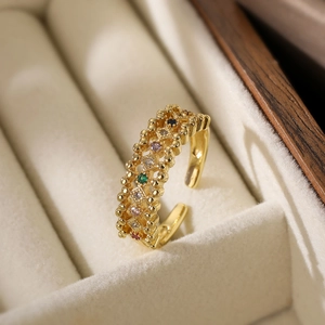 Detail of gold open ring with multi-color zircon stones on cream velvet jewelry box