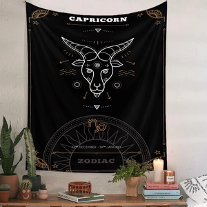Detail of black Capricorn zodiac tapestry with gold celestial symbols on white wall decor