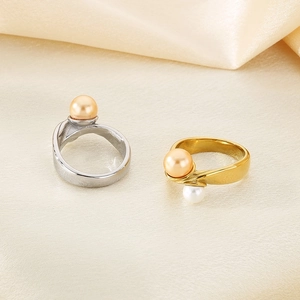 Detail of silver and gold pearl rings on beige silk fabric with elegant warm lighting