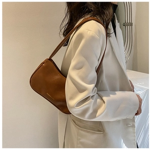 Side view of elegant brown leather shoulder bag on model with cream blazer detail