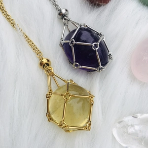 Detailed view of gold and silver crystal cage pendants on a soft white fur background