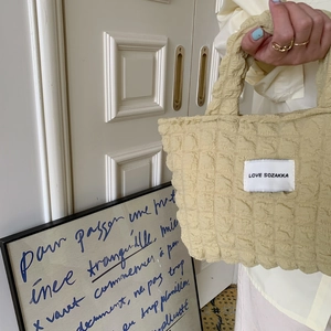Detailed view of bubble texture canvas handbag with minimalist brand label and soft handle