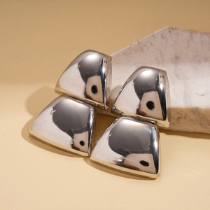 Macro shot of silver geometric trapezoid earrings resting on white marble stone