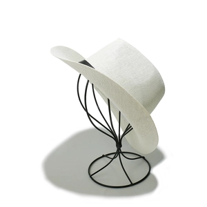 Detail of white woven straw fedora hat featuring black ribbon on metal display stand