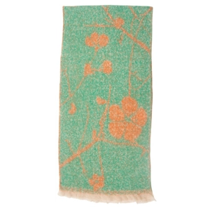 Close-up of green boucle scarf featuring orange floral patterns and fringed tassel edges