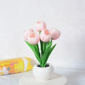 Detail of pink LED tulip night light in white ceramic pot with realistic green leaves