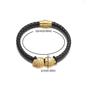 Detail of black woven leather bracelet with gold skull charms and size markings