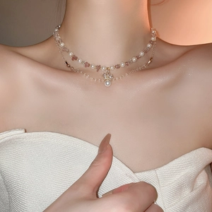 Detail of layered gold necklace with pearls, pink stones and crown zircon pendant on neck