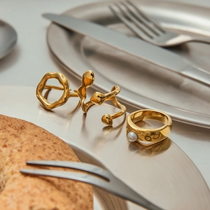 Detailed view of three gold titanium rings featuring white pearls and organic fluid shapes