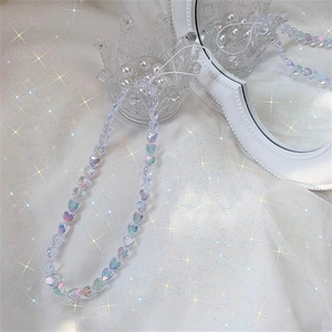 Macro shot of colorful iridescent heart-shaped acrylic beaded phone charm on a crystal stand