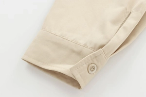 Detailed close-up of light khaki twill shirt cuff with precise stitching and a matching button