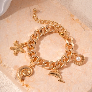 Close-up of a gold-plated bracelet featuring starfish, shell, and dolphin charms