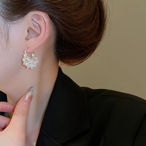 Close-up of model wearing pearl basket hoop earrings with elegant woven texture