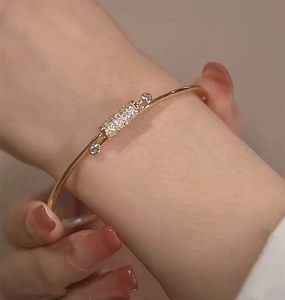 Macro detail of gold knot bracelet with micro-paved cubic zirconia on a female wrist