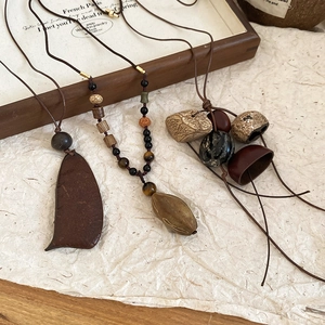 Macro shot of ethnic vintage necklaces with natural wood, stones, and seeds on kraft paper