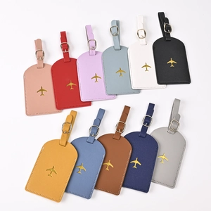 Flat lay showing multiple colors of faux leather luggage tags with gold airplane icons
