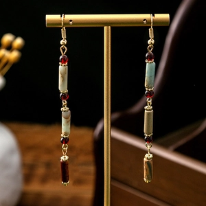 Detail of long drop earrings featuring bamboo-shaped stones and colorful beaded tassels