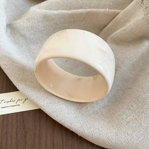 Close-up of cream acrylic resin bangle with marble texture on vintage wooden table