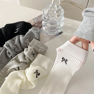 Detail of soft rib-knit Christmas socks with delicate bow embroidery and elastic cuff