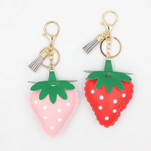 Détail de porte-clés fraise en cuir PU avec pompons et fermoirs mousquetons dorés