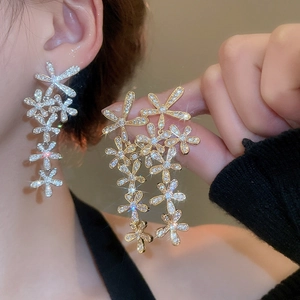 Detailed view of silver and gold flower tassel earrings with sparkling rhinestones