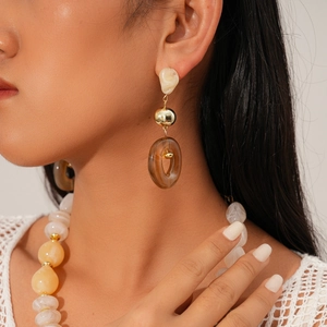 Macro detail of retro long pendant earrings with amber resin and gold bead on a model