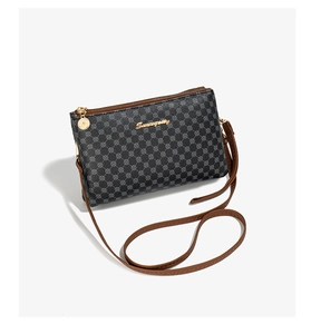 Detail of printed crossbody bag showing dark gray faux leather and brown piping edge
