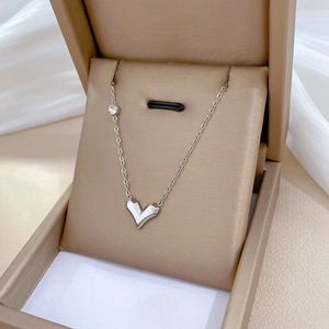 Detailed shot of a silver heart-shaped origami pendant necklace in a brown jewelry box