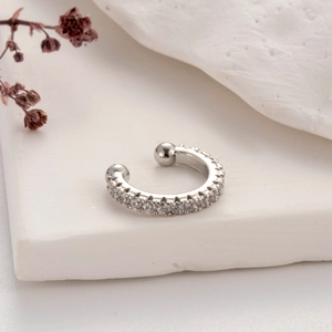 Macro shot of silver ear cuff with micro-pave cubic zirconia on a white stone base