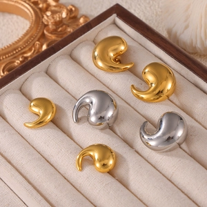 Polished geometric comma earrings in gold and silver finish on a jewelry box