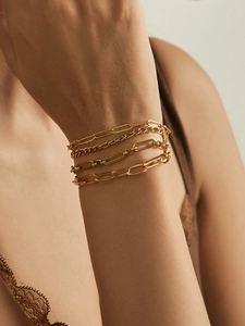Detail of four-piece gold bracelet set including snake, Cuban, and paperclip chains