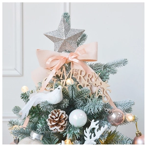 Close-up of pink bows, wooden Merry Christmas sign, and pine cones on a snowy tree
