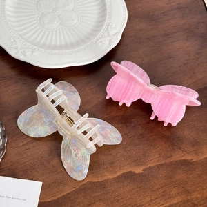 Iridescent butterfly hair claws and pink marbled acetate clips on a decorative plate