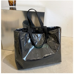 Close-up of glossy black jelly tote bag with green text detail and reinforced handles