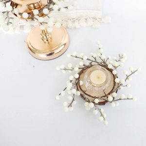 Détail macro de couronne de baies blanches avec bougeoir en verre sur socle en bois