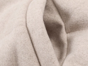 Detailed macro shot of beige wool cashmere fabric showing soft texture and premium stitching