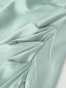 Primo piano del liscio tessuto di raso verde menta con eleganti trame plissettate