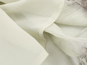 Detailed macro view of ivory lace fabric and fine stitching on a summer mini dress