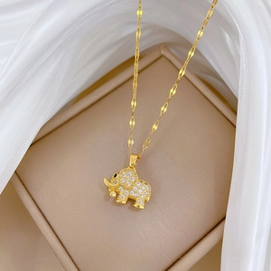 Close-up of gold elephant pendant with micro-inlaid crystals on beige jewelry box with silk