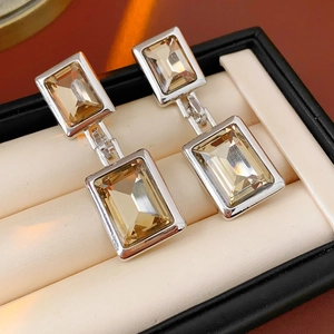 Detailed close-up of champagne zircon square drop earrings in a premium jewelry box