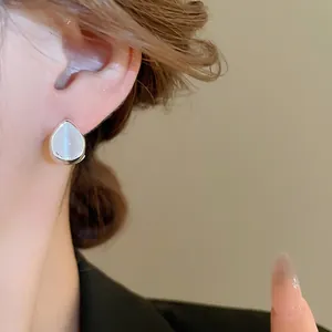 Minimalist silver teardrop cat eye stone earrings worn by a model in soft lighting