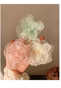 Detailed view of handmade mesh flower hair clips in mint green, pink, and off-white colors