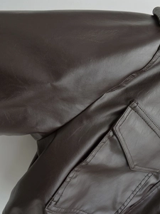 Close-up of the flap pocket and fine faux leather texture on this brown fashion jacket