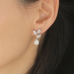 Close-up of elegant silver leaf earrings with marquise crystals worn by a model