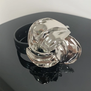 Detail van zilveren abstracte metalen bloem op zwarte leren armband met reflectie