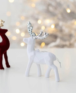 Close-up of white flocked Christmas reindeer with silver glitter antlers and bokeh lights
