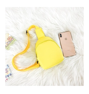 Yellow PU leather mini crossbody bag for kids with adjustable strap on plush background