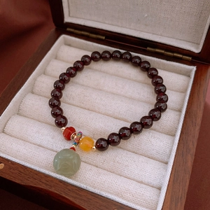 Detailaufnahme von Granatperlenarmband mit hohlgeschnitztem Lotus-Jadeanhänger